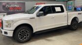 White Ford F-150 pickup with FX4 Off Road badge, inside a showroom under a Turn & Burn Motors sign.